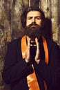 Caucasian hipster in suit holding perfume on brown vintage wooden studio background