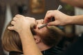 Bearded man with long beard getting stylish hair shaving , haircut , with razor by barber in barbershop Royalty Free Stock Photo