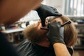 Bearded man with long beard getting stylish hair shaving , haircut , with razor by barber in barbershop Royalty Free Stock Photo