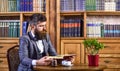 Bearded man in luxury suit in old library.