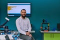 A bearded man in a modern robotics laboratory, immersed in research and surrounded by advanced technology and equipment