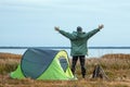 A bearded man near a camping tent in green on the background of nature and the lake. The concept of travel, tourism, camping Royalty Free Stock Photo