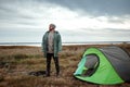 A bearded man near a camping tent in green on the background of nature and the lake. The concept of travel, tourism, camping Royalty Free Stock Photo