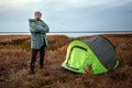 A bearded man near a camping tent in green on the background of nature and the lake. The concept of travel, tourism, camping Royalty Free Stock Photo