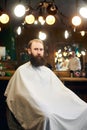 Male client with beard sitting in hairdresser chair. Serious man with long brown beard. Modern popular lumberjack style. Royalty Free Stock Photo