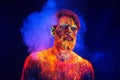 Bearded man painted in fluorescent powder on a background of smoke