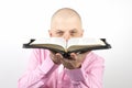 Bearded man in a pink shirt looks through an open Bible Royalty Free Stock Photo