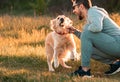 Handsome man with a dog golden retriever walk in spring meadow