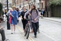 A bearded man in a purple shirt is walking with a bicycle in front of a crowd of girls with bouquets of flowers Royalty Free Stock Photo