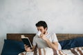 Bearded man reading a big book lying in his bedroom.