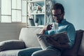 Bearded Man Reading Newspaper on Gray Sofa at Home Royalty Free Stock Photo