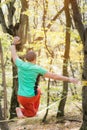 A bearded man in return is developing balance while walking along the slackline in the autumn forest on a sunny day. The