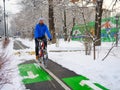 A bearded man rides a bicycle along a bike path in a park in winter Royalty Free Stock Photo