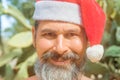 Close-up portrait of smiling, well tanned, bearded caucasian man in a Santa Claus hat standing in front of cacti on the