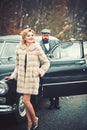 Bearded man and sexy woman in fur coat. Escort of girl by security. Retro collection car and auto repair by mechanic