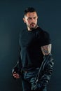 Bearded man show tattoo on strong arm. Tattooed man in tshirt and leather jacket. Fashion macho with beard on unshaven