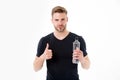 Bearded man show thumbs up with bottle of water. Thirsty man with beard in tshirt hold plastic bottle. Thirst and Royalty Free Stock Photo