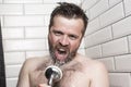 Bearded man singing in the bathroom using the shower head with f Royalty Free Stock Photo