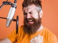 Bearded man sings in condenser microphone at recording studio. Emotional Male professional vocalist. Royalty Free Stock Photo