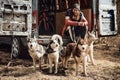 Bearded man sits in back of truck in front of four Siberian Husky dogs, dryland sled dog team