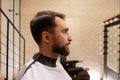 Bearded man sits in front of a mirror in barbershop