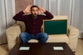 Bearded man sitting on the couch at home with a blackboard with his thumb down