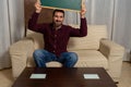 Bearded man sitting on the couch at home with a blackboard with his thumb down