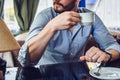 Bearded man sitting with cup of morning coffee and looking out the window
