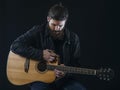 Bearded man sitting playing an acoustic guitar