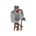 Bearded man sitting on wooden chair leaning on ax and thinking. Thoughtful lumberjack in gray sweater, blue jeans and