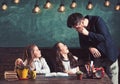 Bearded man and small girls in elementary school. Teacher teach schoolgirls in classroom. Children students study at Royalty Free Stock Photo