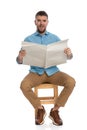 Bearded man with sneakers reading newspaper and grimacing Royalty Free Stock Photo