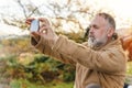 Man in speshial boots reaching the destination and resting under tree and taking photos on phone in Peak District at Royalty Free Stock Photo