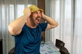 Bearded man in a straw hat dressed in a dark blue shirt with an expression of fury in the living room at home Royalty Free Stock Photo