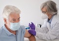 Bearded man with surgical mask getting vaccinated, covid-19 from a female doctor.  Coronavirus vaccination concept Royalty Free Stock Photo