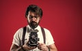 bearded man in suspenders making vintage photo. elegant businessman hold retro camera. journalist use old technology