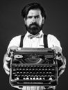 bearded man in suspenders with retro typewriter. brutal guy in bow tie. elegant male typist. handsome hipster use