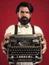 bearded man in suspenders with retro typewriter. brutal guy in bow tie. elegant male typist. handsome hipster use