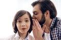 Bearded man tells secret to ear of teenager. Royalty Free Stock Photo