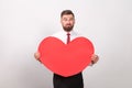 Bearded man thoughtful, holding red heart and thinking of love