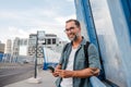 Bearded man using phone while waiting for bus. Royalty Free Stock Photo