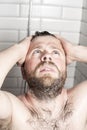 Bearded man washing her hair in the shower under running water.