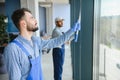 bearded man washing office windows near blurred multicultural women, banner