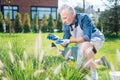 Bearded man wearing beige shorts and sneakers enriching soil in the garden