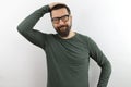 Bearded man wearing casual clothes and glasses confuse and wonder about question. uncertain with doubt, thinking with hand on head