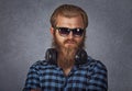 Bearded man wearing sunglasses and headphones. Studio shot on grey background Royalty Free Stock Photo