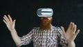 Bearded man wearing virtual reality headset and having 360 VR experience on black background Royalty Free Stock Photo