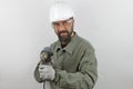 Bearded man wearing worker uniform and hardhat holding drill tool Royalty Free Stock Photo
