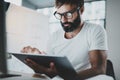 Bearded man in white tshirt working with portable electronic pro tablet computer at modern lightful office.Horizontal Royalty Free Stock Photo