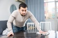 Bearded man wiping table with rag in room Royalty Free Stock Photo